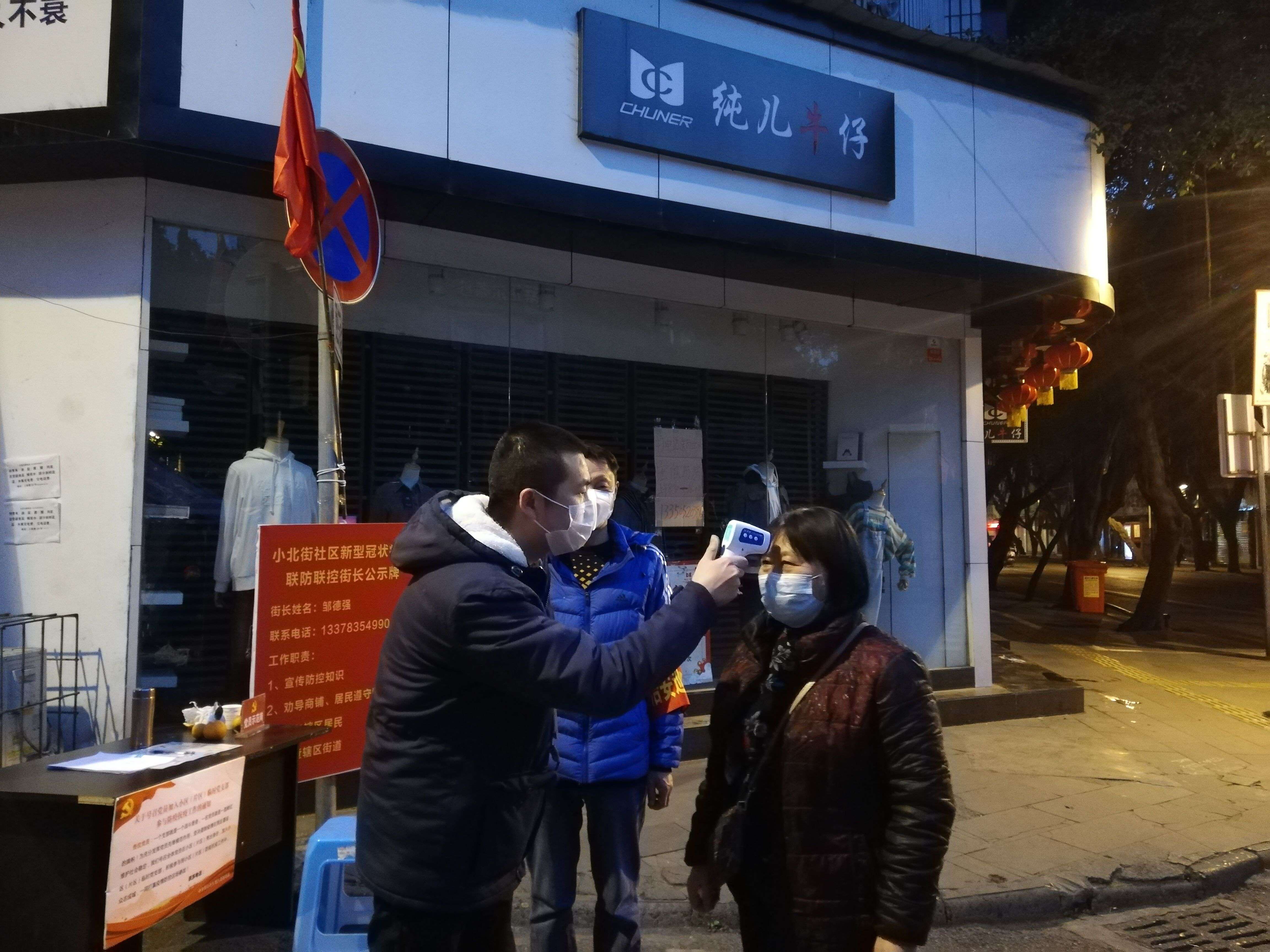 苏祠街道干部罗欢在防控卡点为进出群众测量体温.jpg
